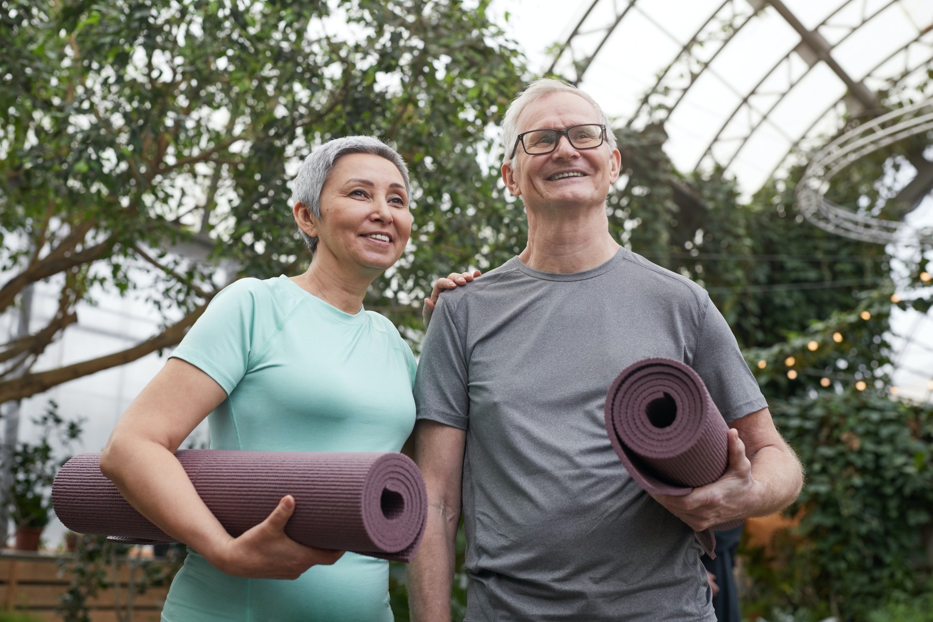 couple smiling while holding yoga mats