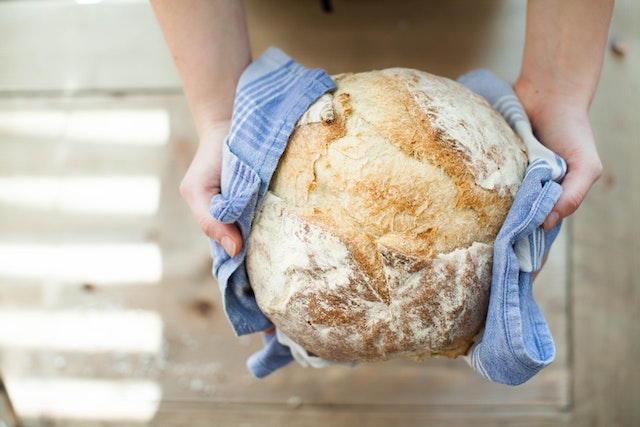 Hands holding a fresh loaf of bread