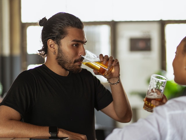 man drinking a glass of beer