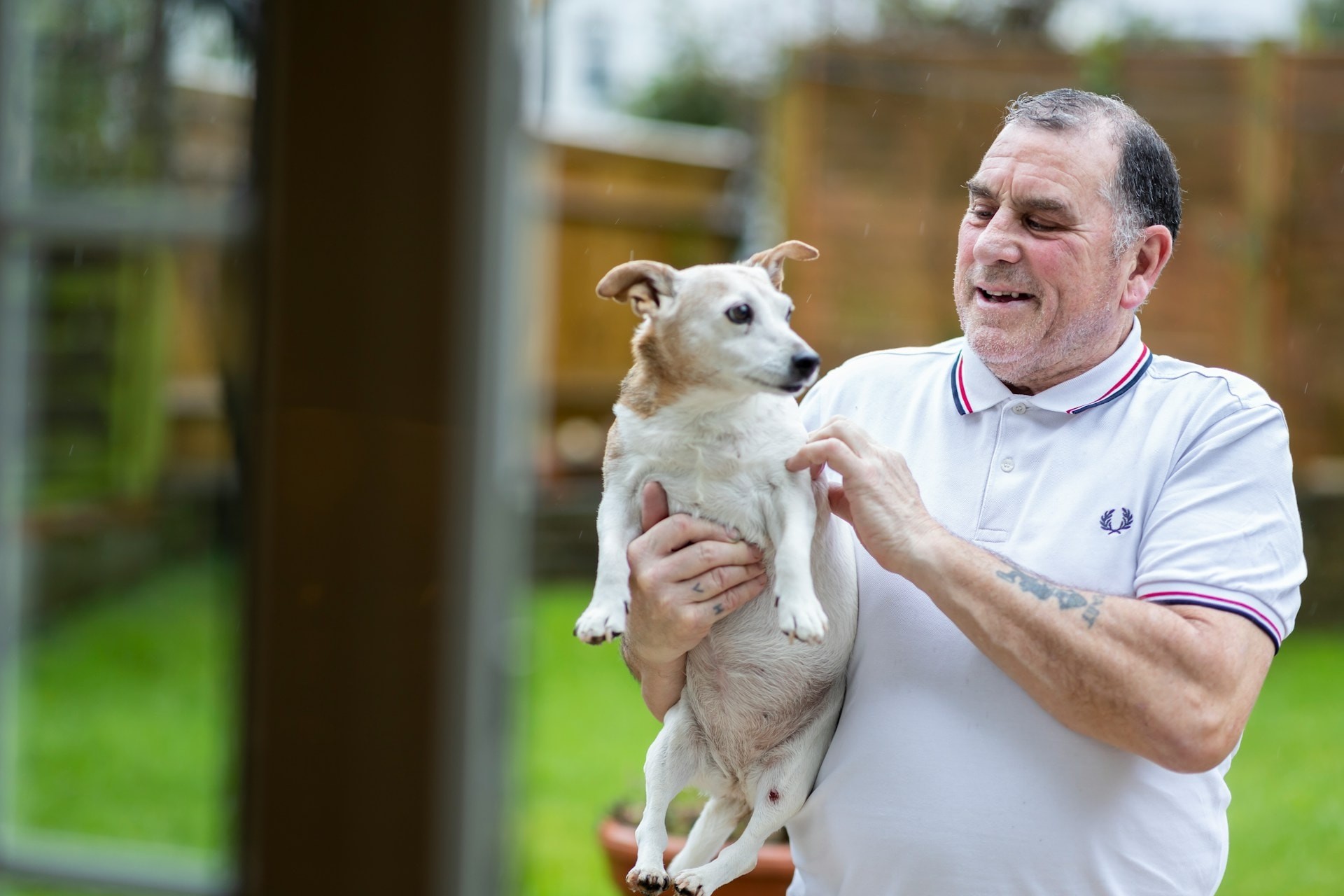 An older man holding a white dog