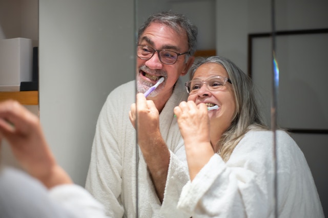 man and woman brushing their teeth