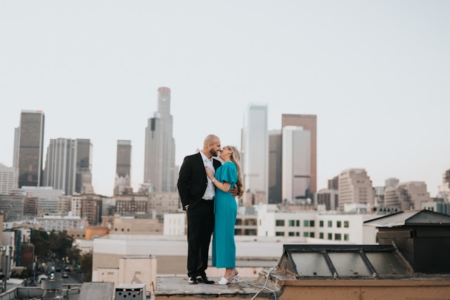 man and woman kissing outside on top of a building