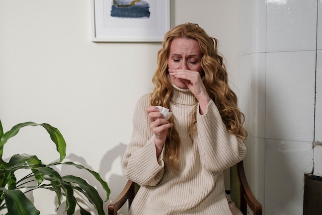 woman with allergies wiping her nose