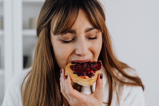 Woman eating toast with peanut butter and jelly