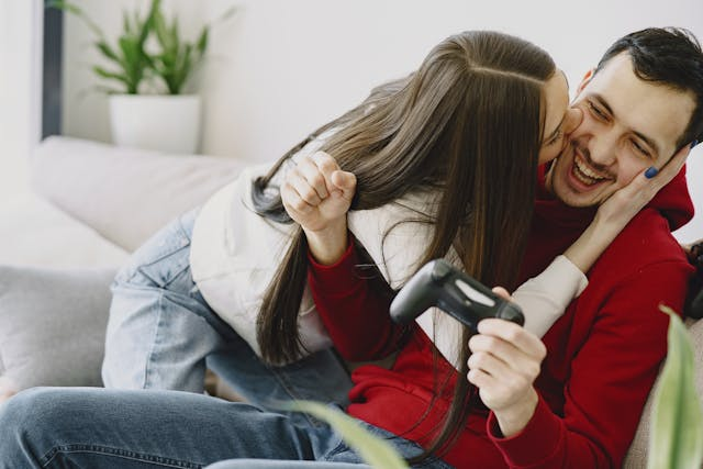 woman kissing a man holding a remote control