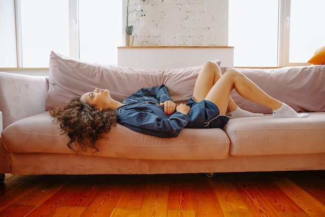 Woman laying on a couch with stomach pain
